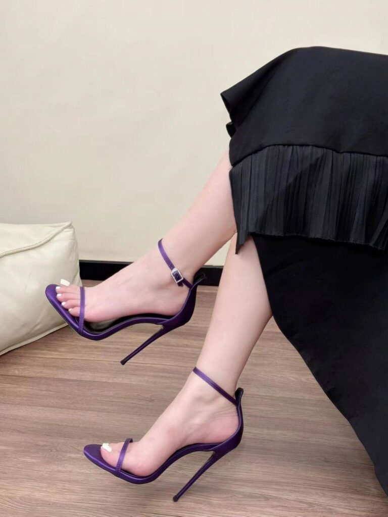 Person wearing purple stiletto high heels with clear straps and ankle straps.