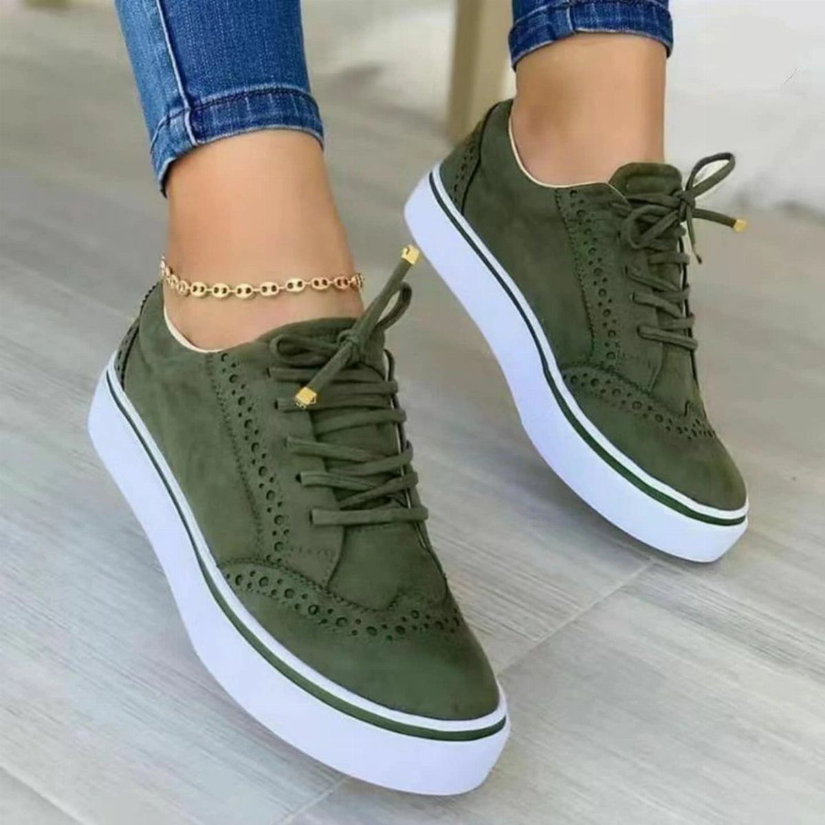 Olive green suede platform sneakers worn with blue jeans and a gold anklet.