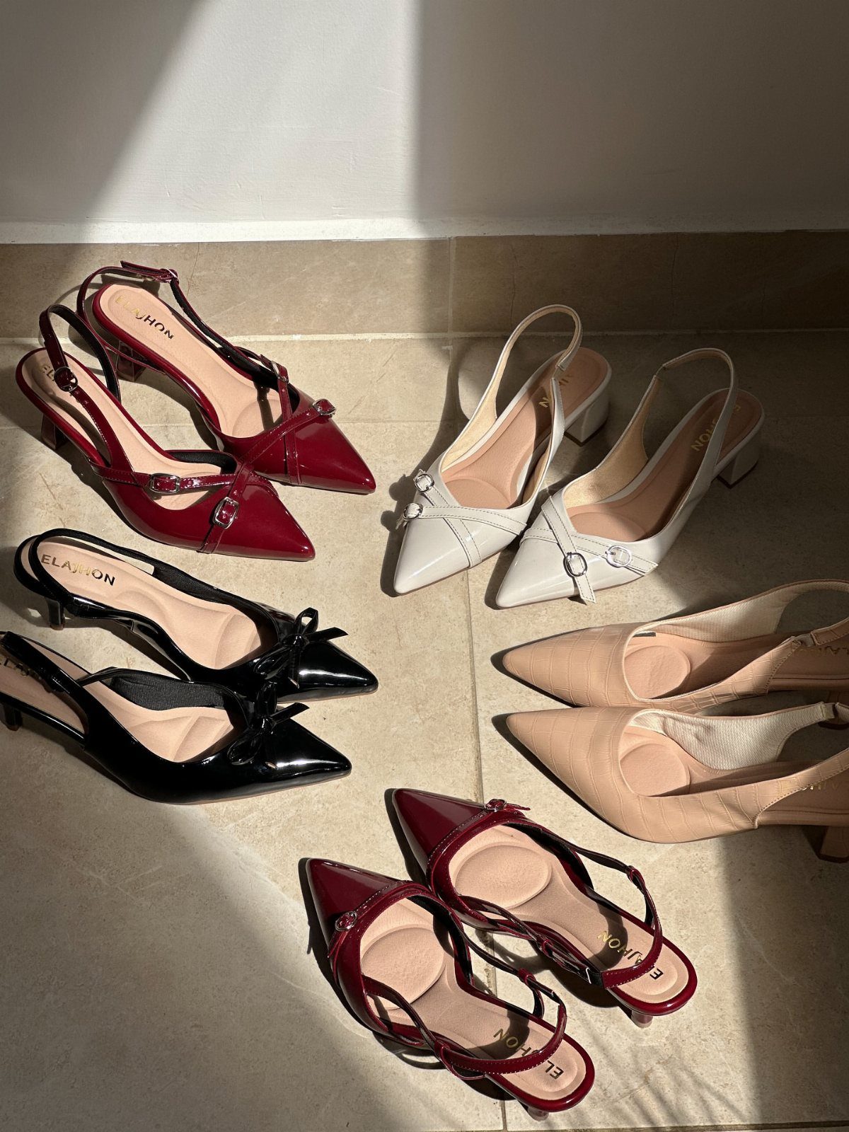 Various pairs of women's pointed-toe slingback heels in red, black, white, and nude colors on a floor.